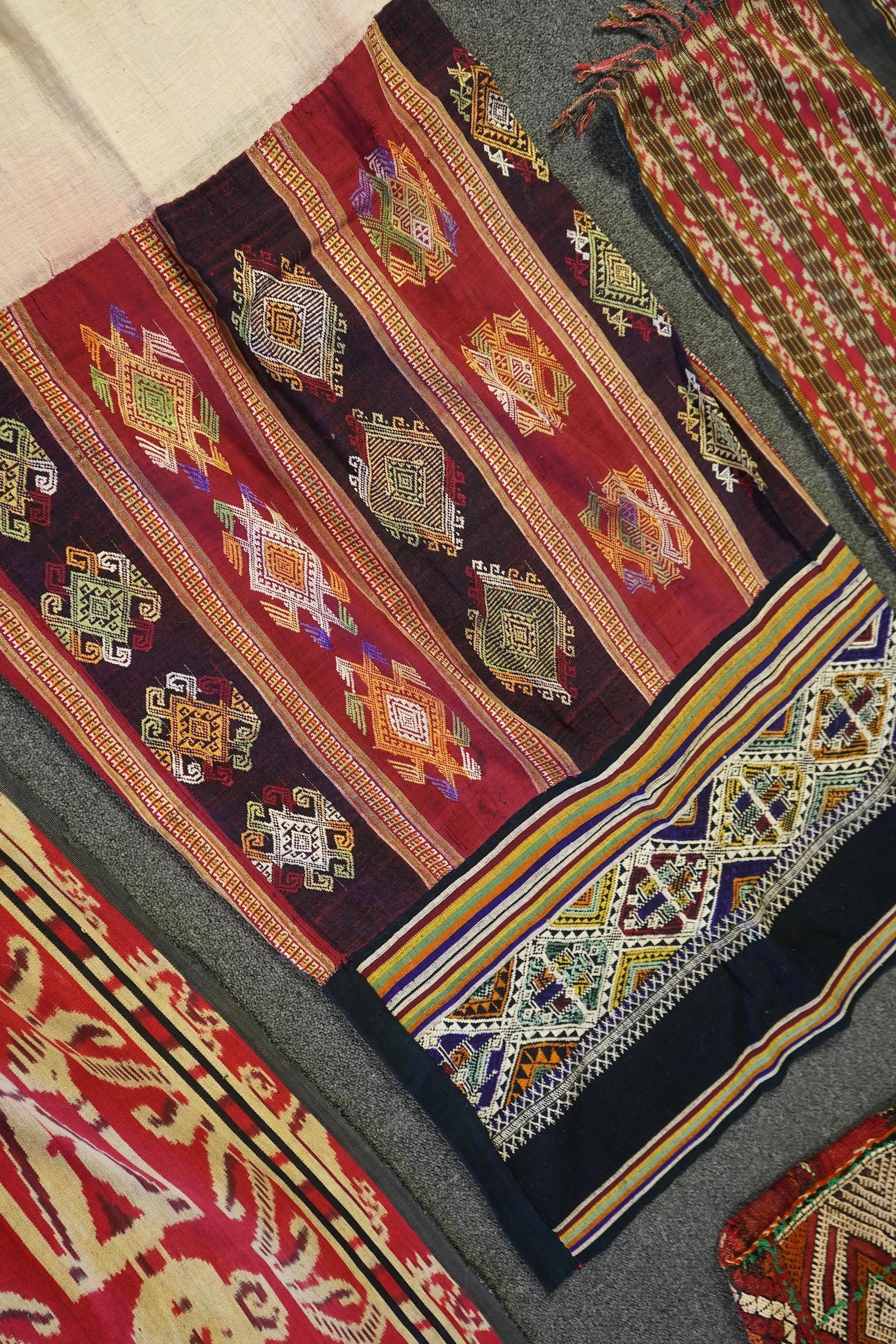 A 20th century Indonesian Sumba single Ikat shoulder cloth, a similar Celebes cloth, a Berber woven skirt and saddle bag and a patchwork cover. (5). Skirt 110cm including hessian top., Condition - some patchwork in the c